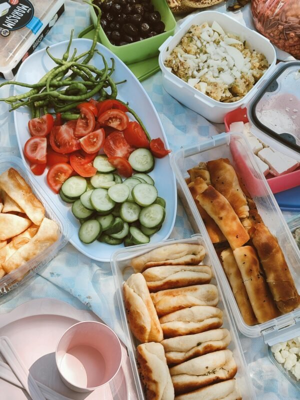 A colorful outdoor picnic spread featuring fresh vegetables, breads, and salads, perfect for a summer lunch.